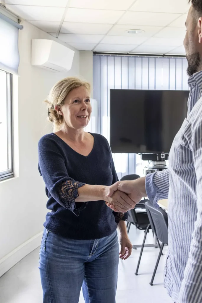 Emmanuelle Monroche accueille un client avec une poignée de main dans son bureau à Angers